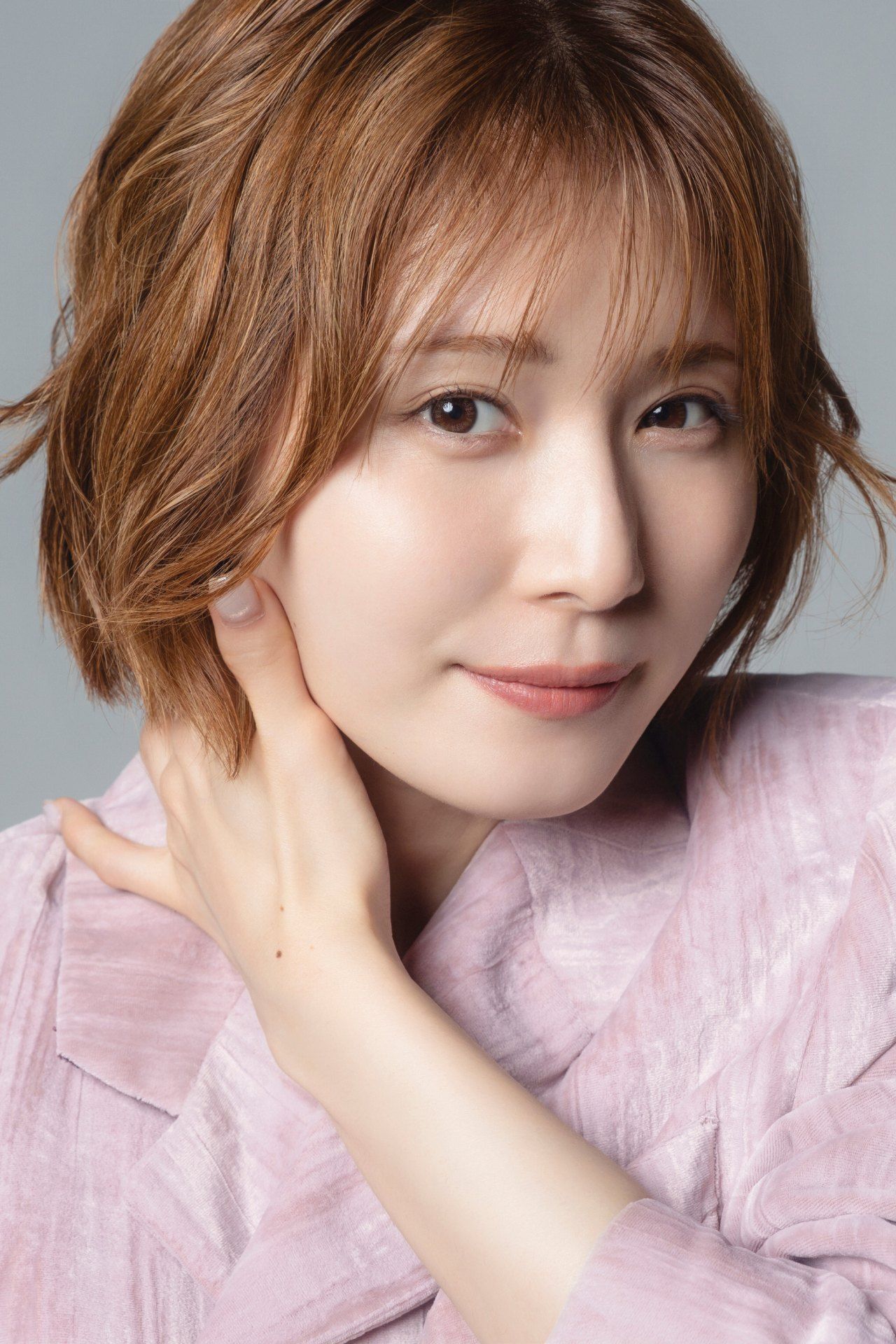 淡いピンクの衣装で頬に手を添え、ほほえむ松岡茉優さん