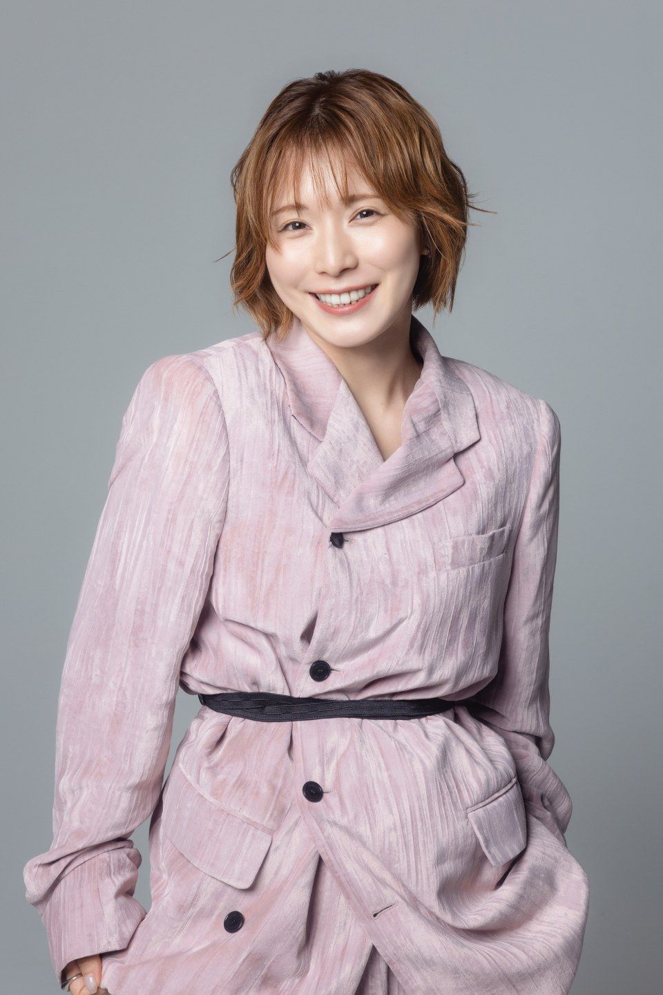 淡いピンクのセットアップ姿で、こちらを見てほほえむ松岡茉優さん